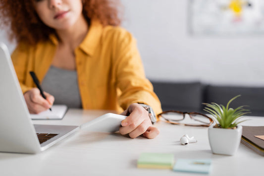 Image of woman at a desk with papers in her hand and a journal reviewing how to resell plr digital products online. 