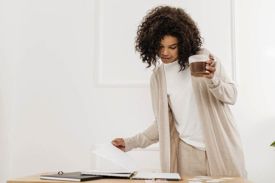 Woman in a cozy beige cardigan holding a cup of coffee, taking a calm moment away from work